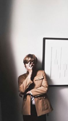 a man standing in front of a white wall with his hands on his face while looking at something