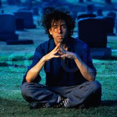 a man sitting on the ground in front of graves