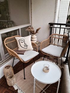 two wicker chairs sitting on top of a wooden floor next to a white table