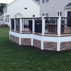 a deck with railings and chairs in the grass near a home's back yard