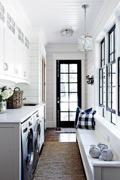 a long narrow hallway with white cabinets and black doors is flanked by a washer and dryer