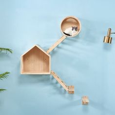 a cat sitting in a wooden house shaped like a birdhouse on a blue wall