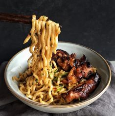 a bowl filled with noodles and meat on top of a table