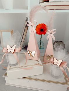 three pink vases sitting on top of each other next to books and a red flower