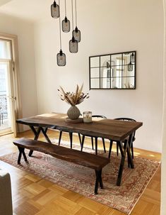 a dining room table and bench in the middle of a living room with hardwood floors