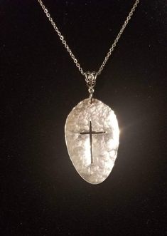 a necklace with a cross in the center on a black background, it is made out of glass