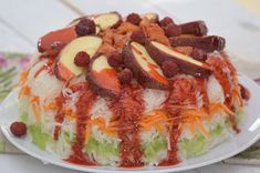 a cake that has been decorated with fruit and vegetables on it, sitting on a white plate