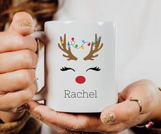 a woman is holding a coffee mug with reindeer's face on it and the words rachel written in black