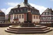 an old building with a fountain in front of it and some buildings around the corner