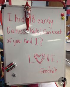 a white board with writing on it and an elf holding a candy cane