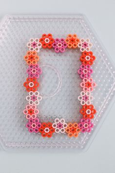 the letter c is made out of plastic beads and sits on top of a hexagonal object