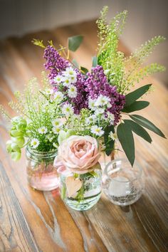 three vases filled with flowers on top of a wooden table