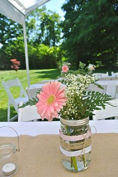 a vase filled with pink flowers sitting on top of a table next to a white chair