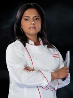 a woman wearing a chef's coat and holding a knife in one hand, with her arms crossed