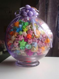 a glass bowl filled with colorful candies on top of a white table next to a window