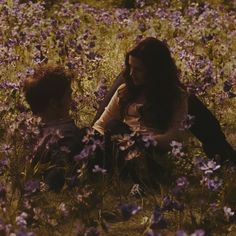 a woman and child are sitting in the middle of a field full of purple flowers