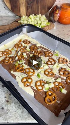 a chocolate cake with pretzels on top is being prepared to be cut into pieces