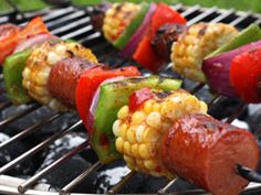 corn on the cob is being grilled on an outdoor bbq with hot dogs