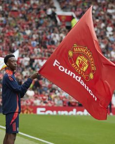 a man holding a manchester united flag on top of a field