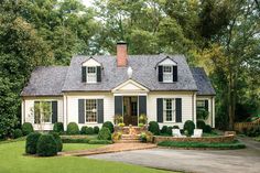 a white house with green shutters and bushes