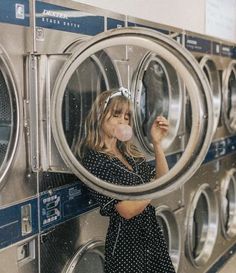 a woman standing in front of a stack of washers with her hand on the door