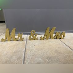 two metal mr and mrs letters on the floor next to each other, one is gold