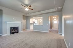 an empty living room with a fireplace and ceiling fan in the middle of the room