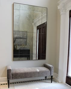 a bench sitting under a large mirror in a room