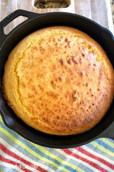 a baked cake in a cast iron skillet on a colorful towel next to a pan