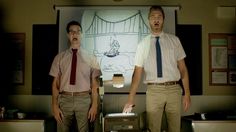 two men standing next to each other in front of a projector screen with their mouths open