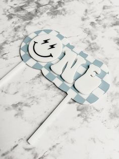 a blue and white cake topper with the word smile on it's face