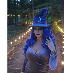 a woman with blue hair wearing a witches hat and dress is posing for the camera