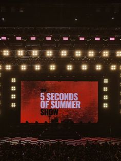 the 5 seconds of summer show is on stage with bright lights and red screen in front of it