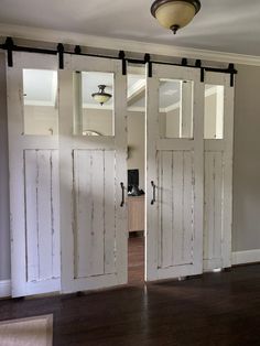 two white doors with mirrors on the side of them in front of a light fixture