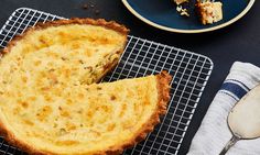 a quiche on a cooling rack next to a plate with two pieces of cake