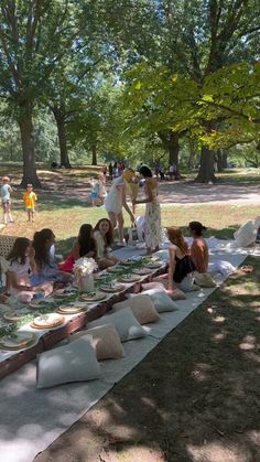 a group of people sitting on top of a grass covered field next to picnic tables