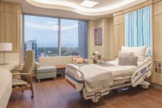 a hospital room with a bed, desk and chair in it's center area