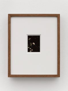 a white wall with a wooden frame holding a black and white photo in it's center