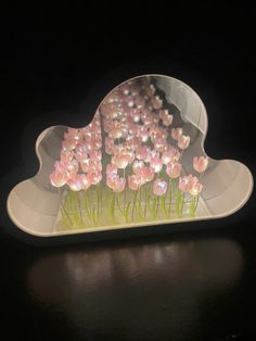 there are pink flowers in the shape of a cloud on top of a black table