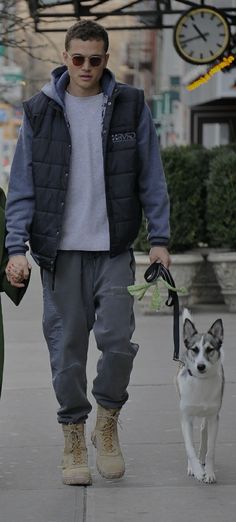 a man and woman holding hands while walking their dog on a leash in the city