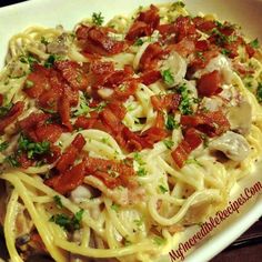 a white bowl filled with pasta covered in sauce and toppings on top of a wooden table