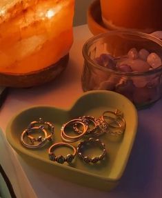 two heart shaped trays with rings on them next to a candle and other items