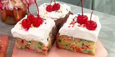 two pieces of cake with white frosting and sprinkles on top, one slice has a cherry