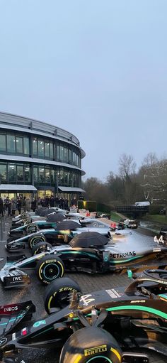 many cars are parked in front of a large building with people standing around it and looking at them