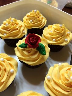 cupcakes with yellow frosting and a red rose on top are arranged in a circle