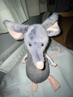 a stuffed animal mouse sitting on top of a bed