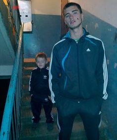 a young man standing next to a little boy on the stairs in front of an escalator