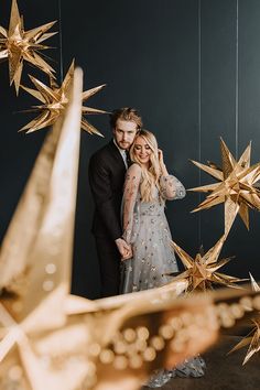 a man and woman standing next to each other in front of golden stars