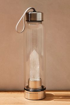 a clear glass jar with a metal base and a small white rock in the bottom