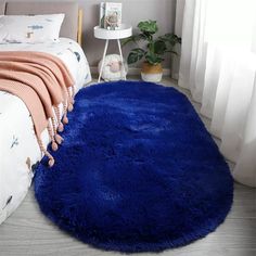 a bright blue rug is on the floor next to a bed with white sheets and pillows